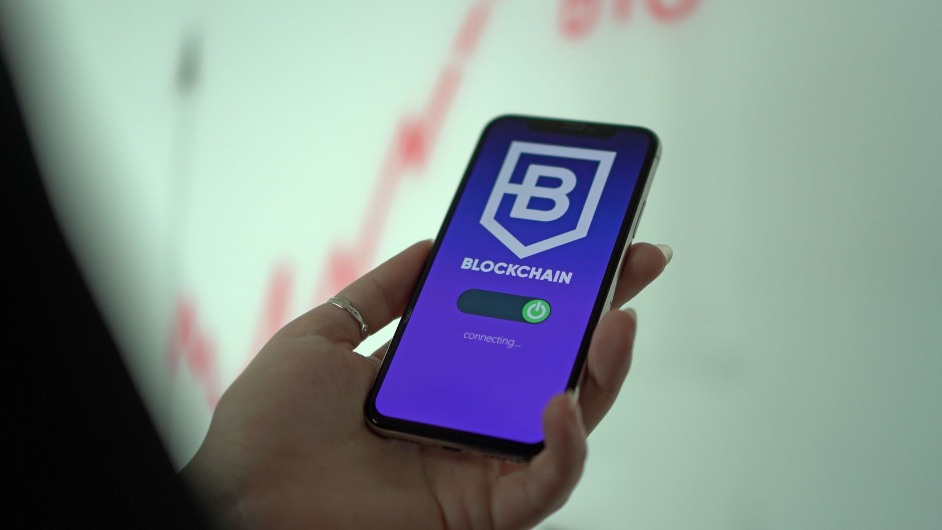 Hand holding a smartphone showing an investment app interface